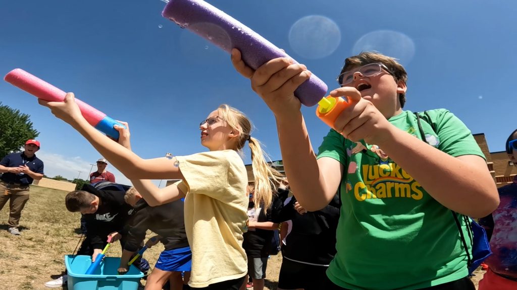 Kids play with squirt guns at the Groundwater Festival, with a lesson on infiltration